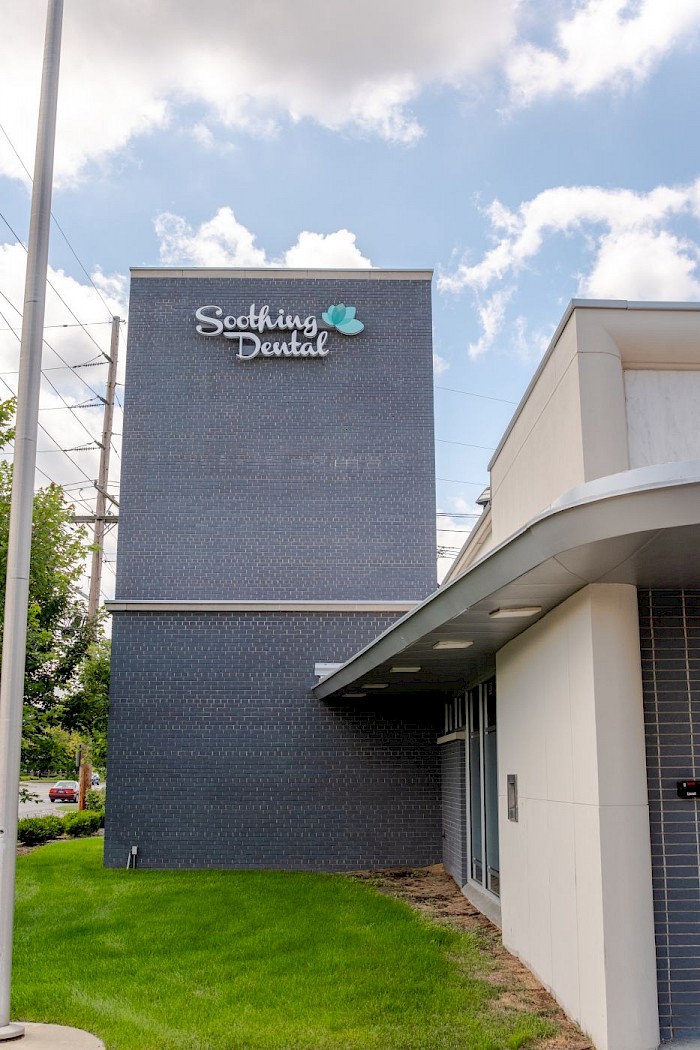 The tall brick sign tower at Soothing Dental carrying the practice name and lotus mark