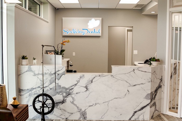 The marble reception counter at Soothing Dental beneath the practice name and lotus mark