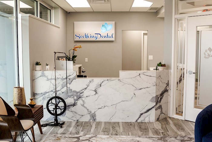 The Soothing Dental reception area, with a marble counter and a wood side table