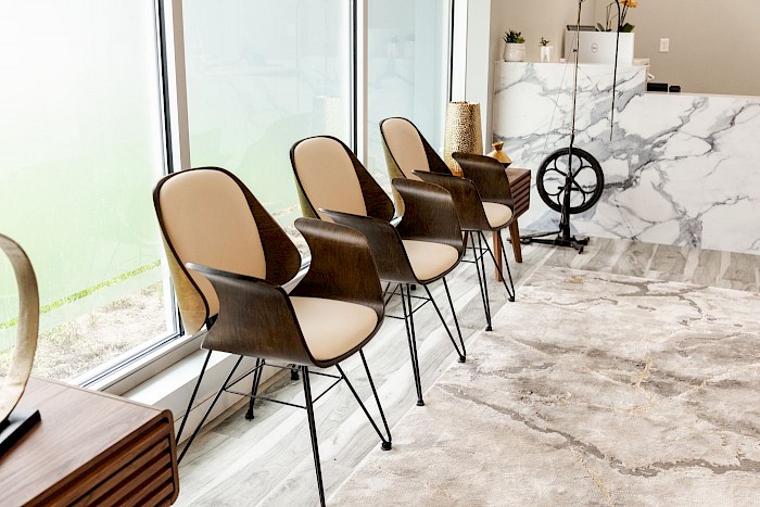 A row of waiting chairs along the window wall at Soothing Dental, beside the marble counter